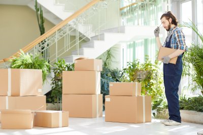 Pensive moving specialist counting delivered boxes